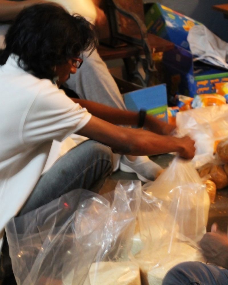 Volunteers sitting on the floor packing groceries into bags for family care kits