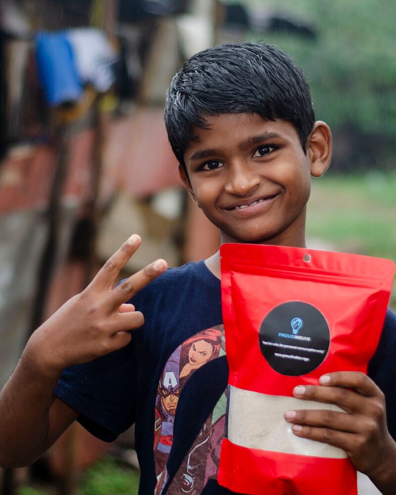 A grinning boy flashing a peace sign with his red nutrition pack at the December 2022 nutrition drive