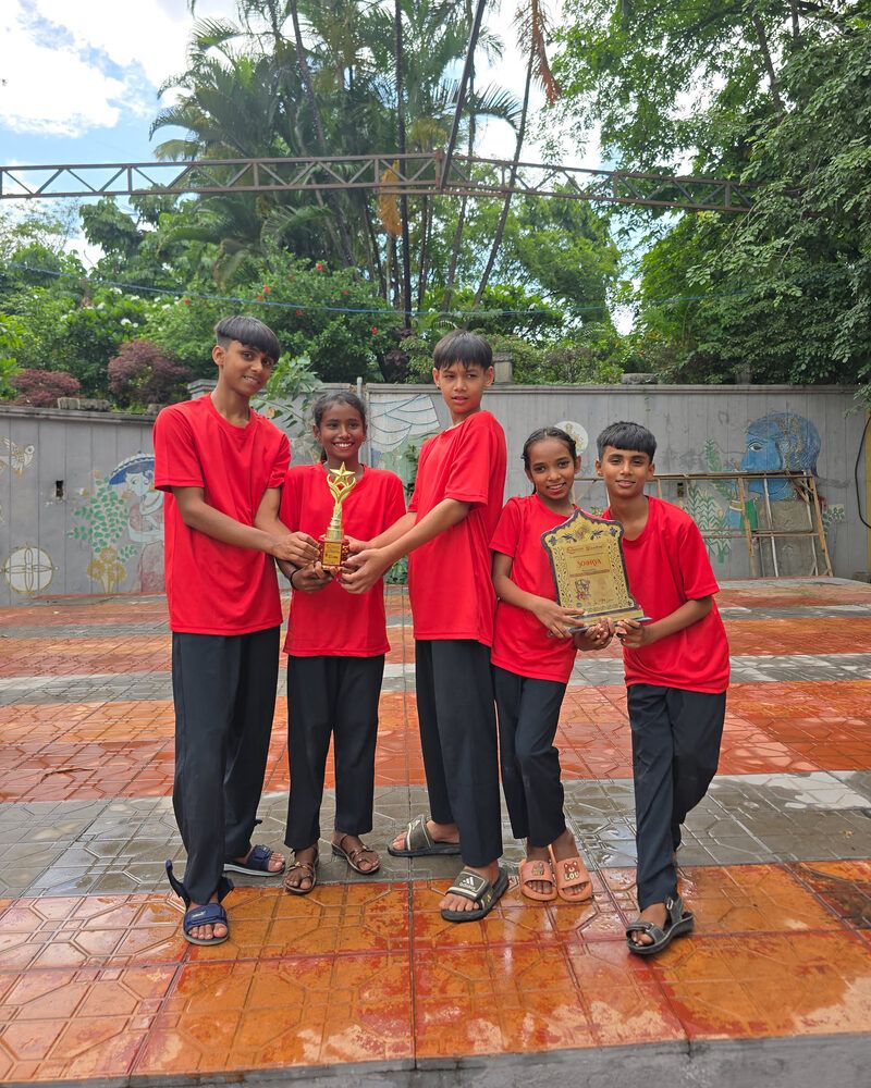 Five children in red T-shirts holding the trophy and certificate they won at the Soorya dance competition