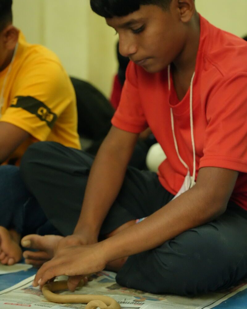 A boy rolling clay on newspaper