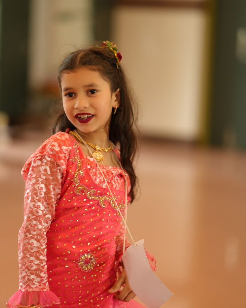 A girl in a sequinned pink dress, smiling mid-dance