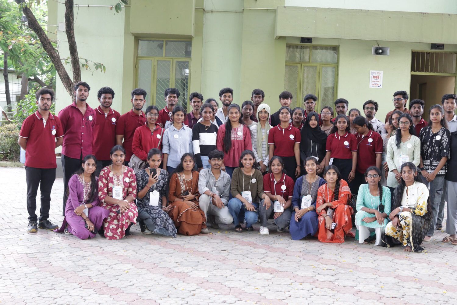 The Kalakriti 3.0 volunteer crew in maroon T-shirts, with children, outside the venue