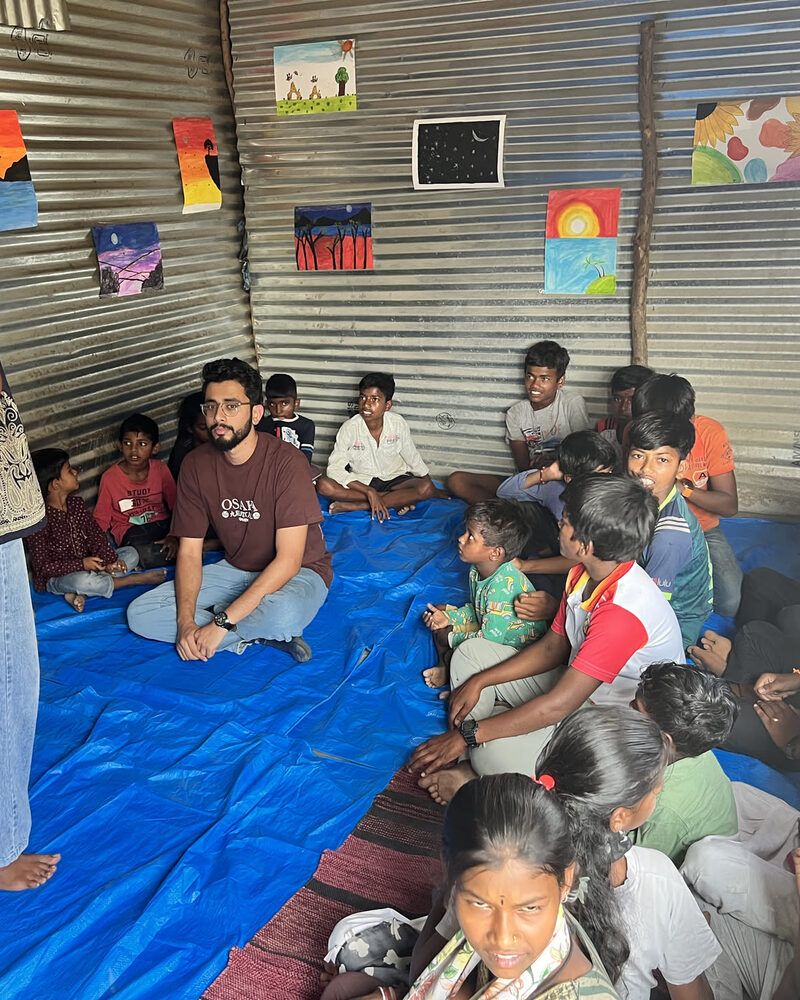 Volunteers sitting in a circle on the floor with children at the community centre